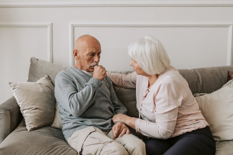 Elderly man coughing next to woman